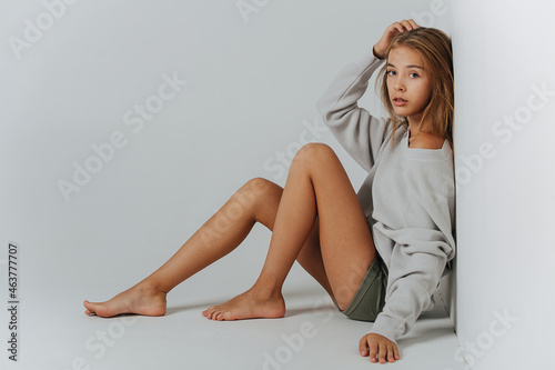 Pretty teenage girl sitting on the floor, leaning her back against the wall photo