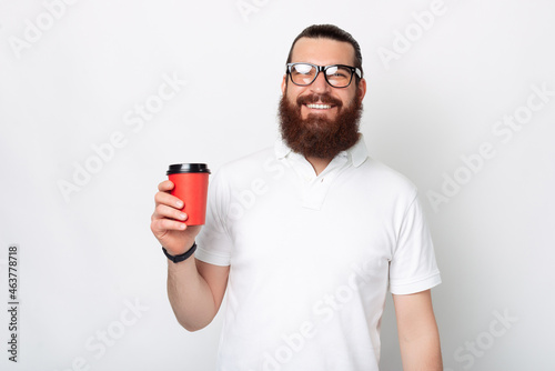 Cheerful man is holding a red hot take away cup of coffee.