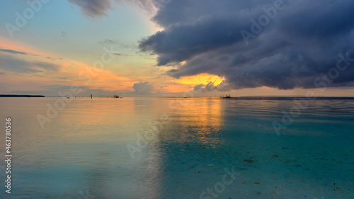 A peaceful and quiet moment at the beach while the golden sunlight starts to appear in the horizon. A calm, serene mood and unique cloud formation of the image can have a soothing and relaxing effect.