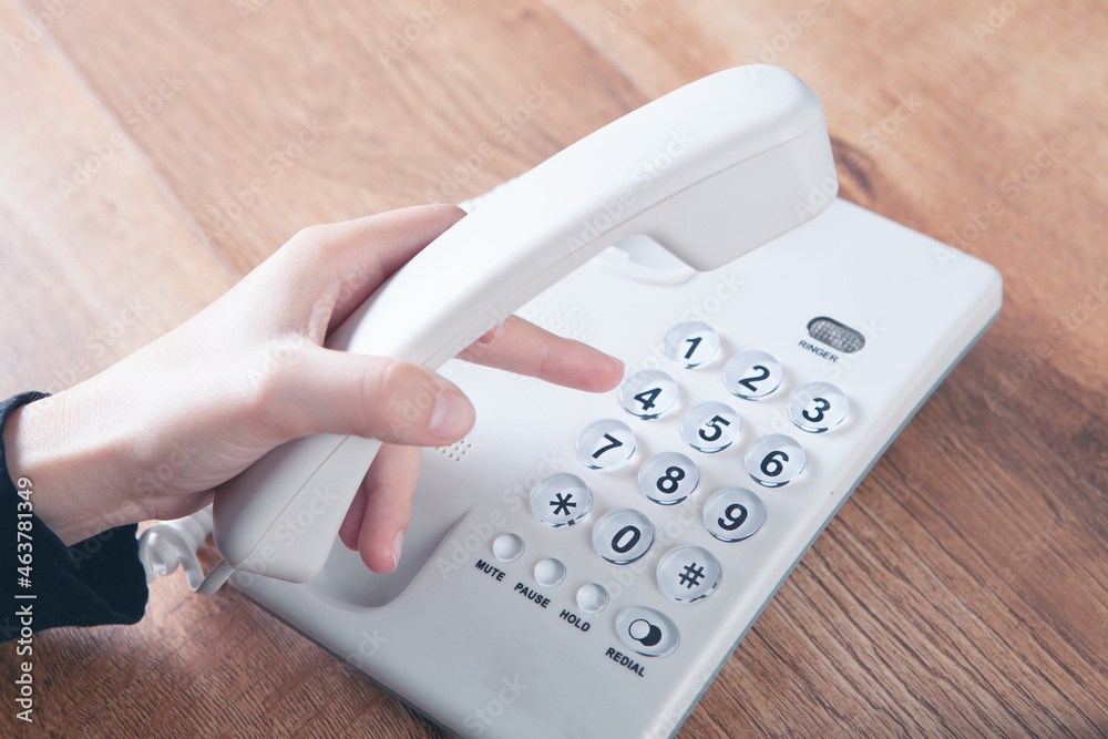 a woman dials a number on a home wired phone a woman dials a number on a home wired phone