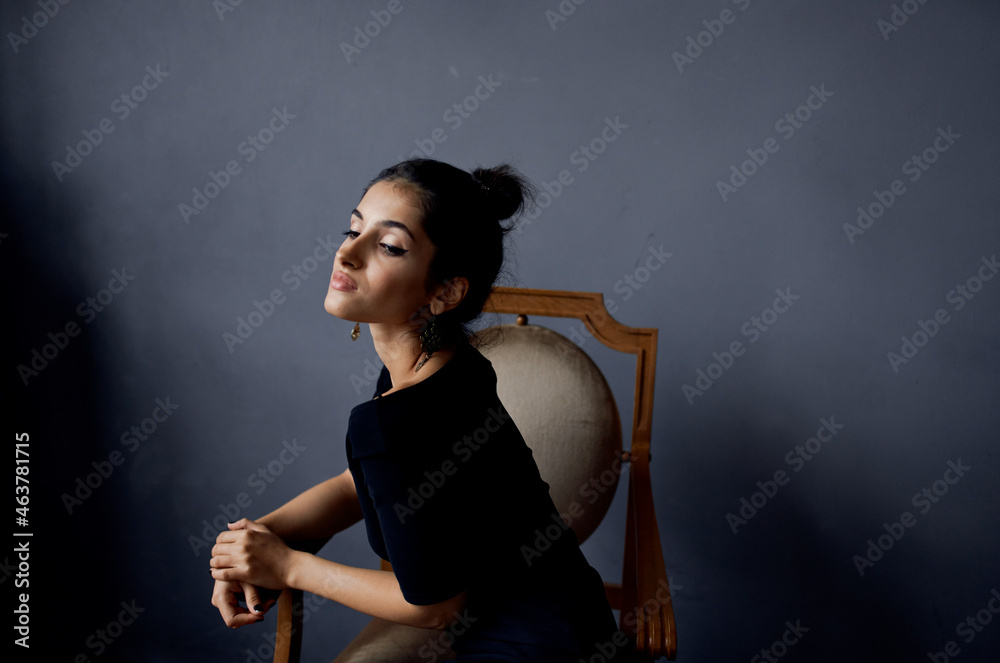 pretty woman earrings jewelry posing near the chair black dress dark background pretty woman earrings jewelry posing near the chair black dress dark background