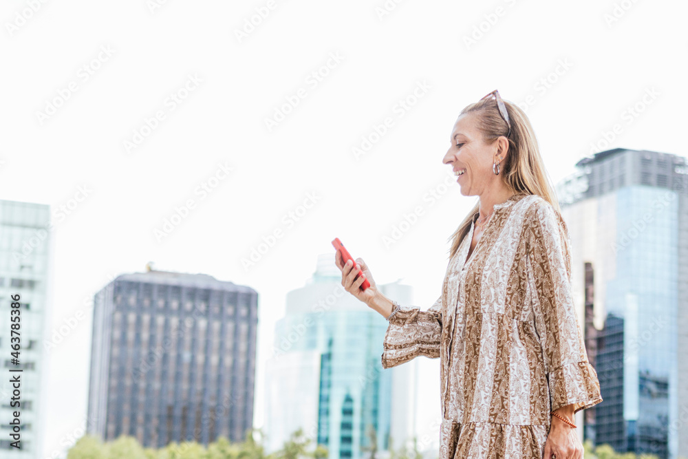 View of woman in autumn clothes using smartphone and standing in the city.