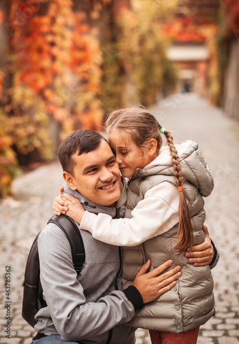 Young happy dad and little daughter hugging in autumn park. Family time, togehterness, parenting and happy childhood concept. Weekend with emotions.