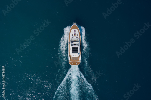 Yacht movement on blue water top view. Luxury yacht on the water aerial view. White yacht fast movement on the water top view. Travel - image. Top view of a white high-speed boat. © Berg