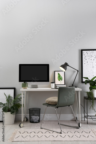 Comfortable workplace with modern computer and houseplants in room. Interior design © New Africa