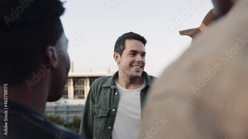 Adult Caucasian Male and Caucasian female chatting with a diverse group of friends at rooftop party. Chatting lightheartedly at sunset. High quality image. photo