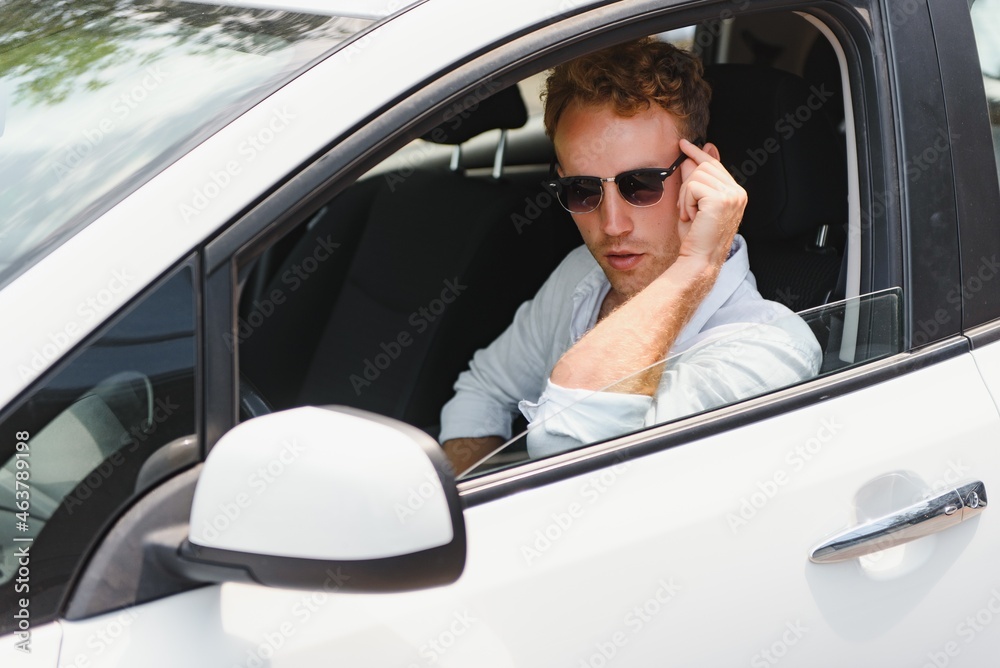Naklejka premium Electric car driver - green energy biofuel concept. Male behind wheel. Man driving new ecofriendly vehicle Young male owner proud confident looking at camera, Taxi driver concept.