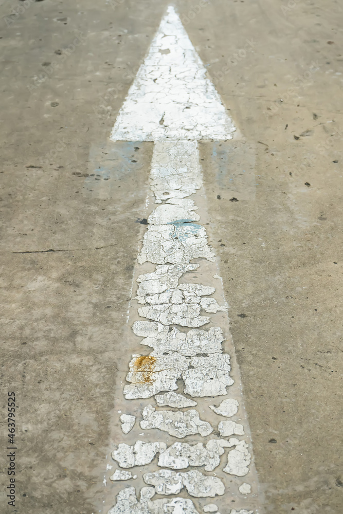 Fototapeta premium White street arrow sign on cement floor at day time
