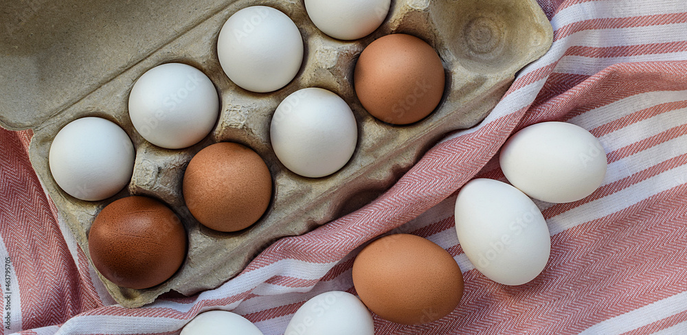 White and brown eggs in a cardboard storage box, close-up. Buying eggs. Top view, flat lay. Selective focus. White and brown eggs in a cardboard storage box, close-up. Buying eggs. Top view, flat lay. Selective focus.