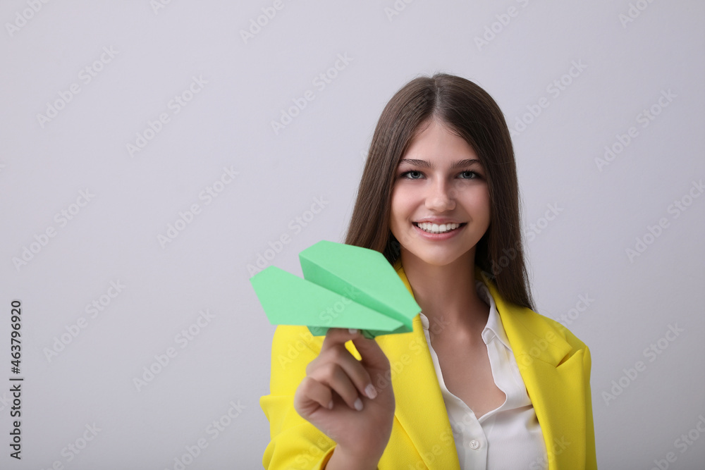 Beautiful teenage girl with paper plane on grey background. Space for text Beautiful teenage girl with paper plane on grey background. Space for text