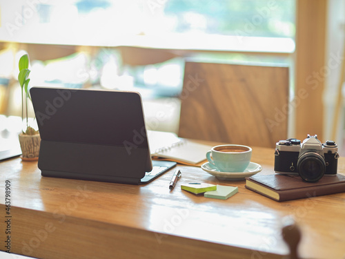 Workspace with digital tablet, vintage camera, coffee cup and stationery