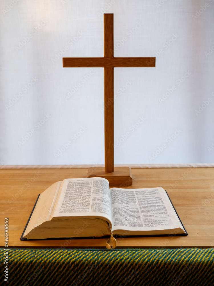 Christian Cross, with the bible in front on wooden table. The bible is in Finnish.
