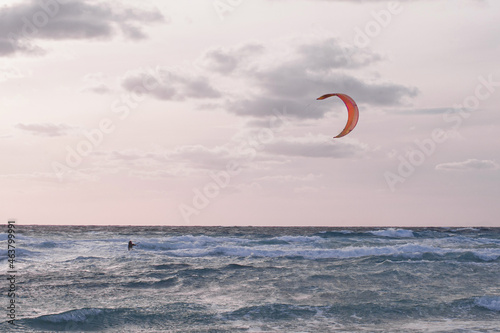 kite surfers in the sky in the evening duck over the blue water of Mediterranean sea