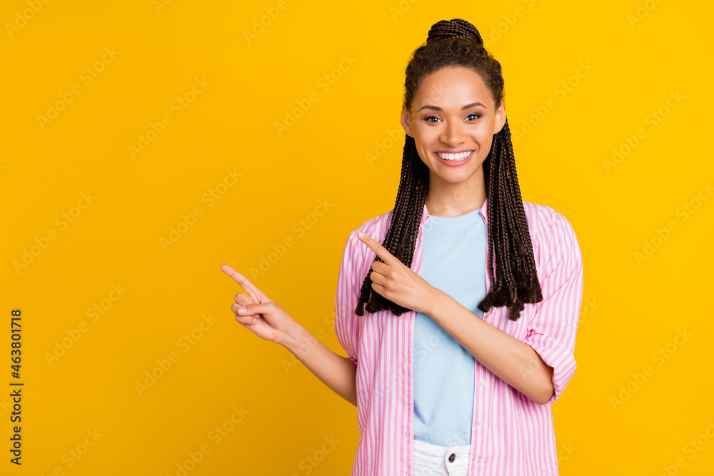 Photo of african lady direct finger empty space wear striped pink shirt isolated yellow color background Photo of african lady direct finger empty space wear striped pink shirt isolated yellow color background