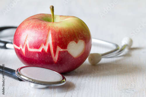 Heartbeat line on red apple and stethoscope, healthy heart diet concept