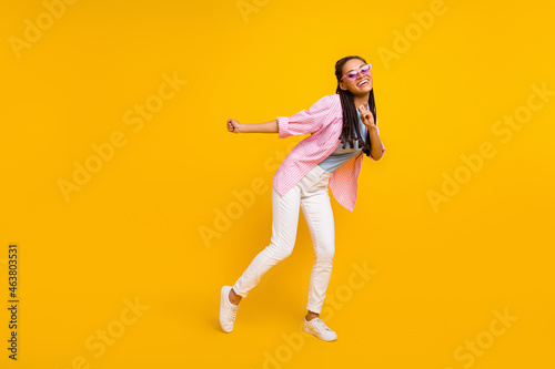 Photo of carefree lovely african lady dance wear sunglass striped shirt isolated yellow color background