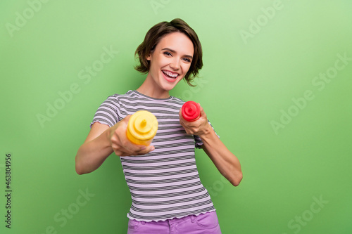 Photo of funky millennial brunette lady press ketchup mustard unhealthy food wear striped t-shirt isolated on green color background