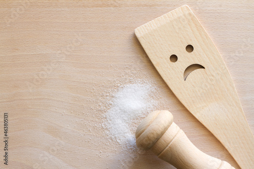 Salt with wooden spoon on cutting board, unhealthy food additives concept photo