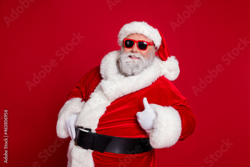 Portrait of attractive cheerful Santa showing thumbup advert ad recommend isolated over bright red color background