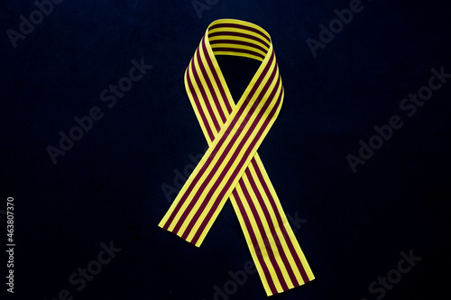 Close-up of a ribbon with the flag of Catalonia forming a bow on a dark background photo