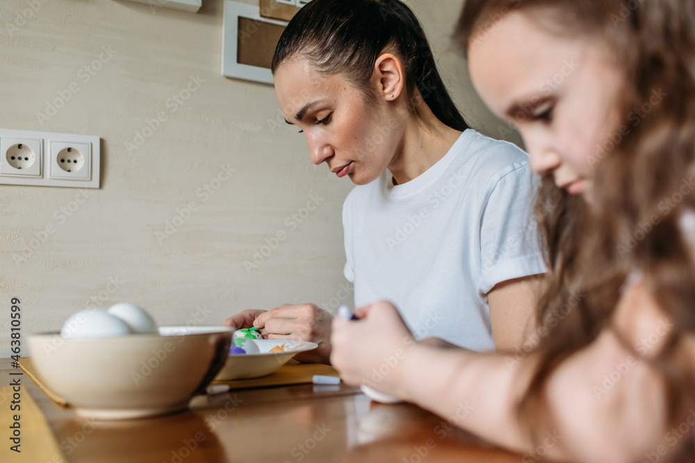family traditions, mother and daughter at the table paint eggs for Easter family traditions, mother and daughter at the table paint eggs for Easter