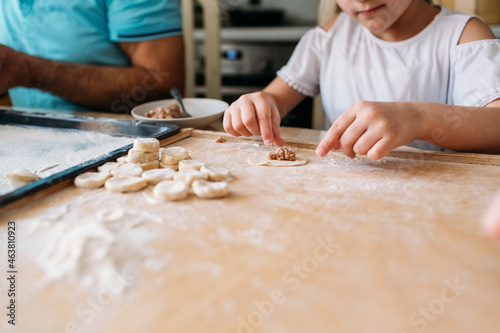 family traditions, grandfather and granddaughter make dumplings together at the table, grandfather helps granddaughter