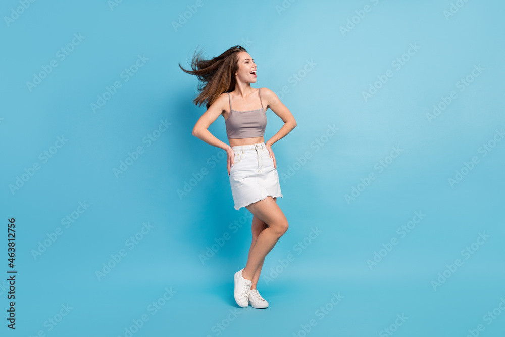 Full length photo of happy charming young woman look empty space summer smile isolated on blue color background Full length photo of happy charming young woman look empty space summer smile isolated on blue color background