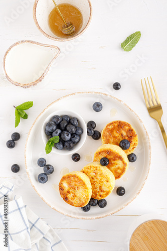 Cottage cheese or curd fritters with honey and fresh blueberry. Healthy diet food, breakfast. Top view.