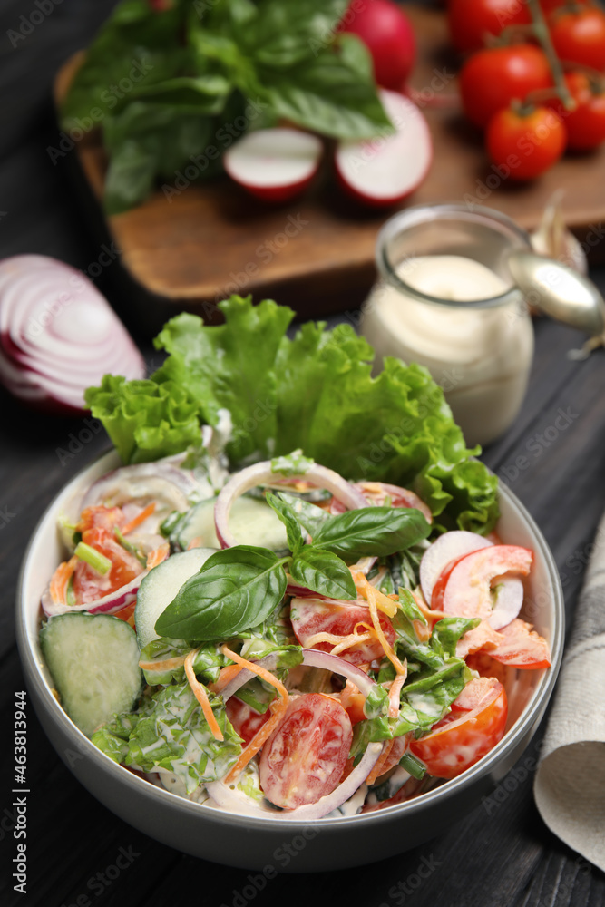 Bowl of delicious vegetable salad dressed with mayonnaise and ingredients on black table - obrazy, fototapety, plakaty 