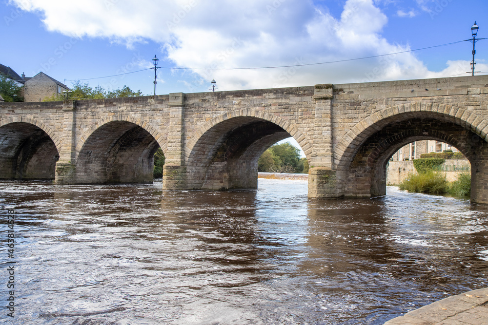 A beautiful old bridge going over the River Wharfe in the British town of Wetherby in Leeds, West Yorkshire in the UK, showing the stone brick bridge going in to the village on a hot sunny summers day