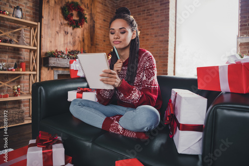 Photo of minded creative lady prepare x-mas gifts wish list think present wear jumper in decorated home indoors