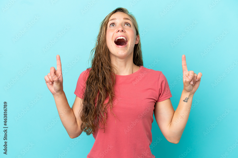 Young caucasian woman isolated on blue background surprised and pointing up Young caucasian woman isolated on blue background surprised and pointing up