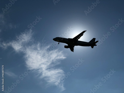 An airplane covering the sun against a blue sky