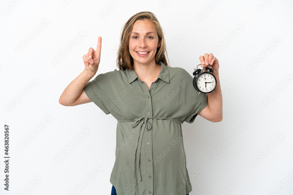 Obraz premium Young caucasian woman isolated on white background pregnant and holding clock while counting one