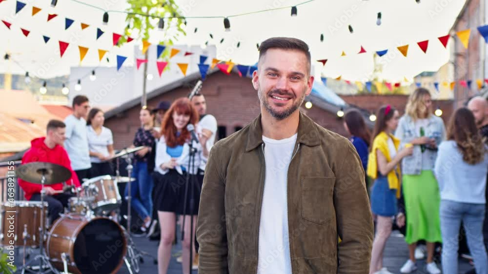 Portrait of young handsome man posing at rooftop party. Attractive male looking and smiling to camera. Concert, roof party, fectival concept Portrait of young handsome man posing at rooftop party. Attractive male looking and smiling to camera. Concert, roof party, fectival concept