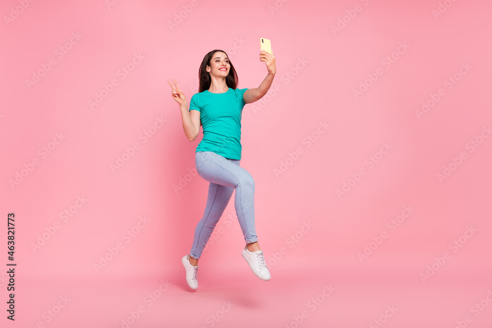 Full size profile side photo of young woman happy smile jump make selfie cellphone show v-sign isolated over pastel color background