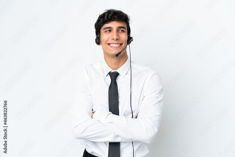 Telemarketer man working with a headset isolated on white background with arms crossed and happy