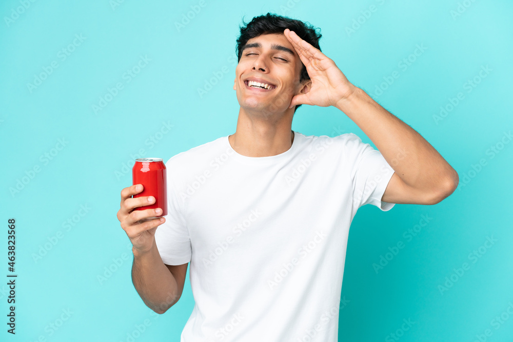 Young Argentinian man holding a refreshment isolated on blue background smiling a lot Young Argentinian man holding a refreshment isolated on blue background smiling a lot