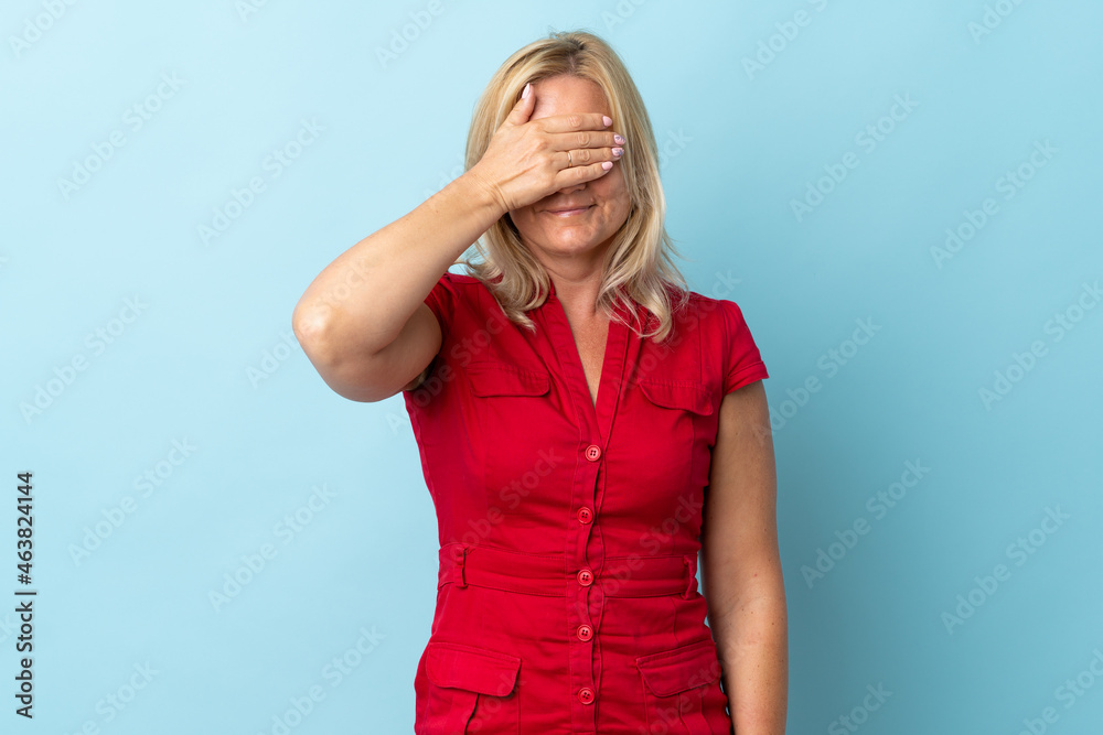 Middle age woman isolated on blue background covering eyes by hands. Do not want to see something Middle age woman isolated on blue background covering eyes by hands. Do not want to see something