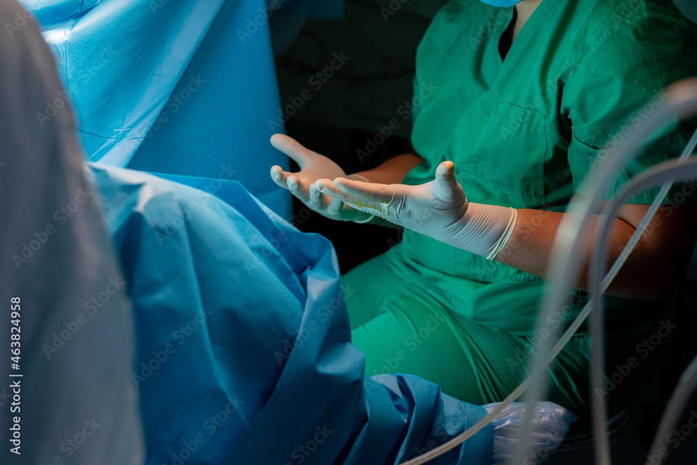 Surgeon's hands in sterile latex gloves. A surgeon in a green uniform pulls forward the spread fingers in sterile surgical gloves. The surgeon's hands during surgery.