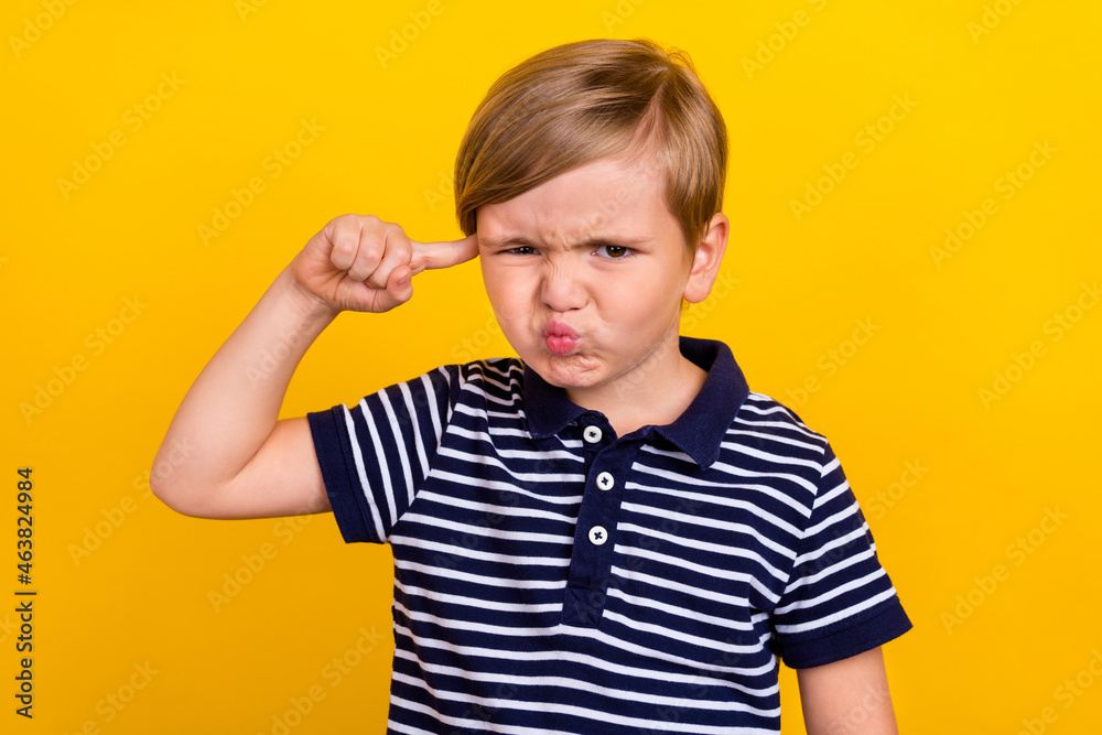 Photo portrait little boy wearing casual clothes abusing keeping finger near forehead isolated vibrant yellow color background Photo portrait little boy wearing casual clothes abusing keeping finger near forehead isolated vibrant yellow color background