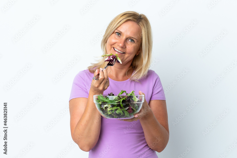 Middle age Lithuanian woman isolated on white background holding a bowl of salad and looking at it with happy expression Middle age Lithuanian woman isolated on white background holding a bowl of salad and looking at it with happy expression