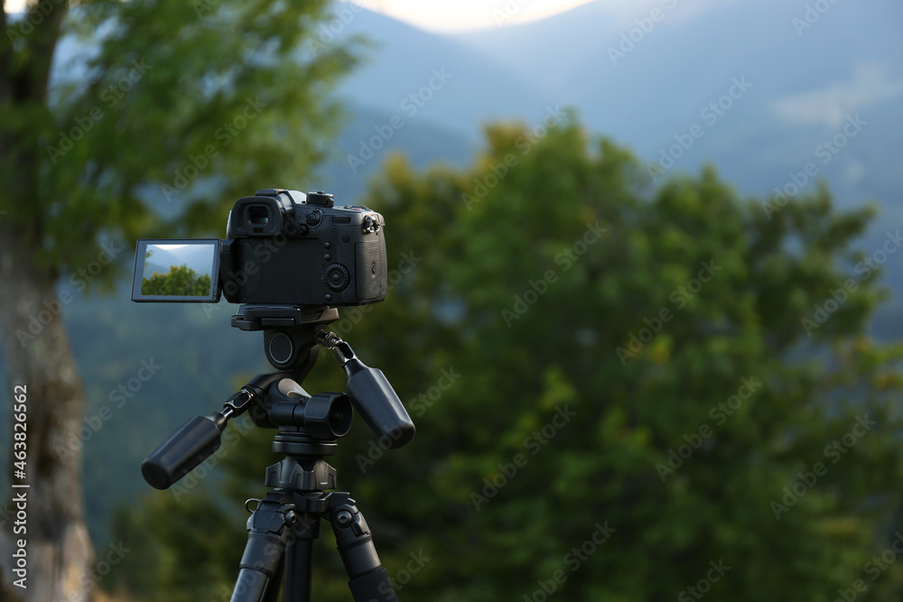 Taking video with modern camera on tripod in mountains