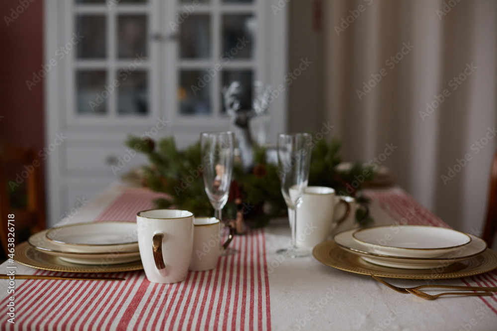 Served table of plates, dishes, wine glasses and cups. Festive dinner table decorated for Christmas