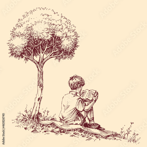 Child reading a book outdoor sitting in the grass under a tree