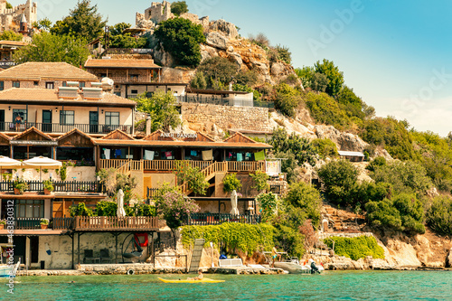 View of a small town on a hillside on which stands the Simena fortress. Turkey, Kekova island. Summer. Boat trip
