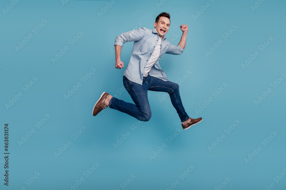 Full size profile side photo of young man have fun jump up go walk run hurry isolated over blue color background