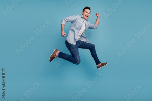 Full size profile side photo of young man have fun jump up go walk run hurry isolated over blue color background © Tetiana