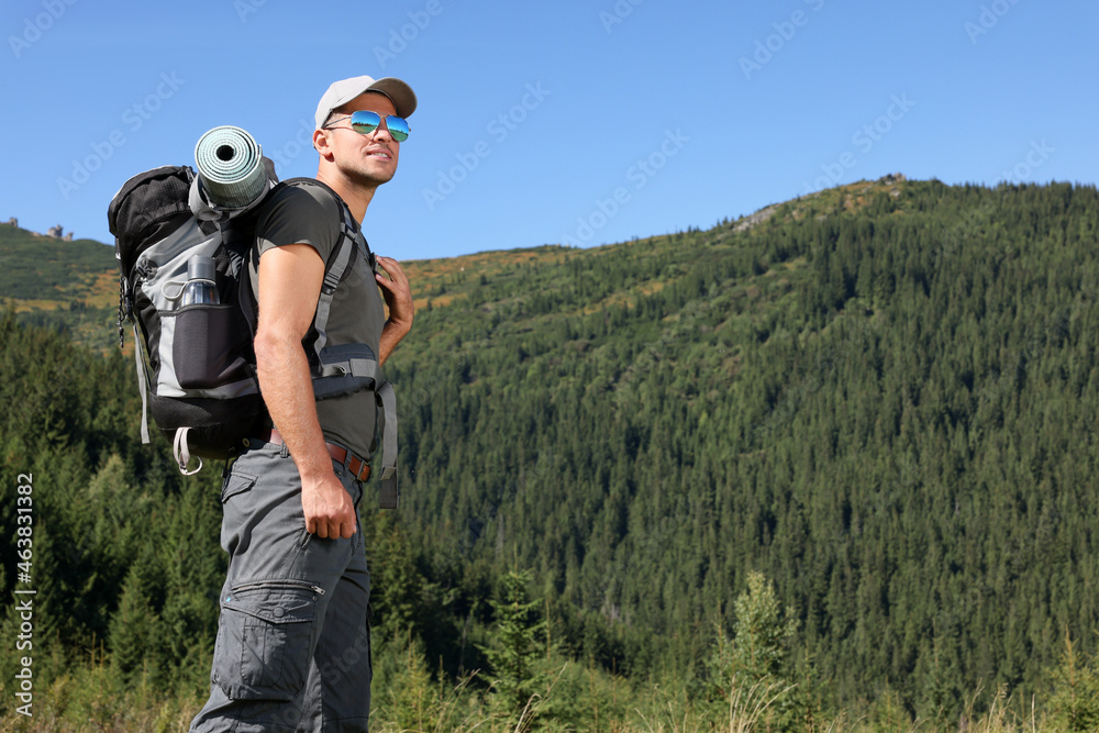 Man with backpack and sleeping mat in mountains. Space for text