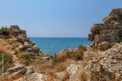 A blue lane of the sea visible between two stone hills with sunburned yellow grass